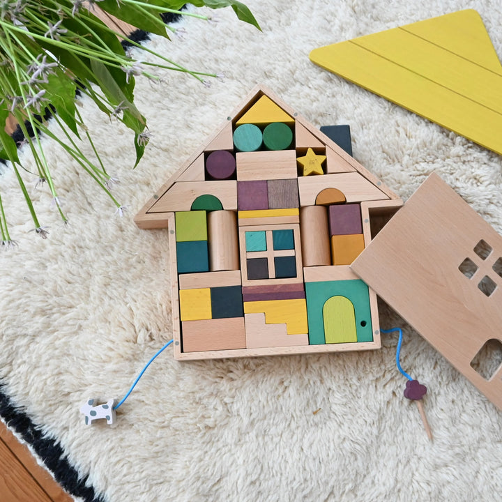 Blocs de construction maison en bois sur un tapis blanc