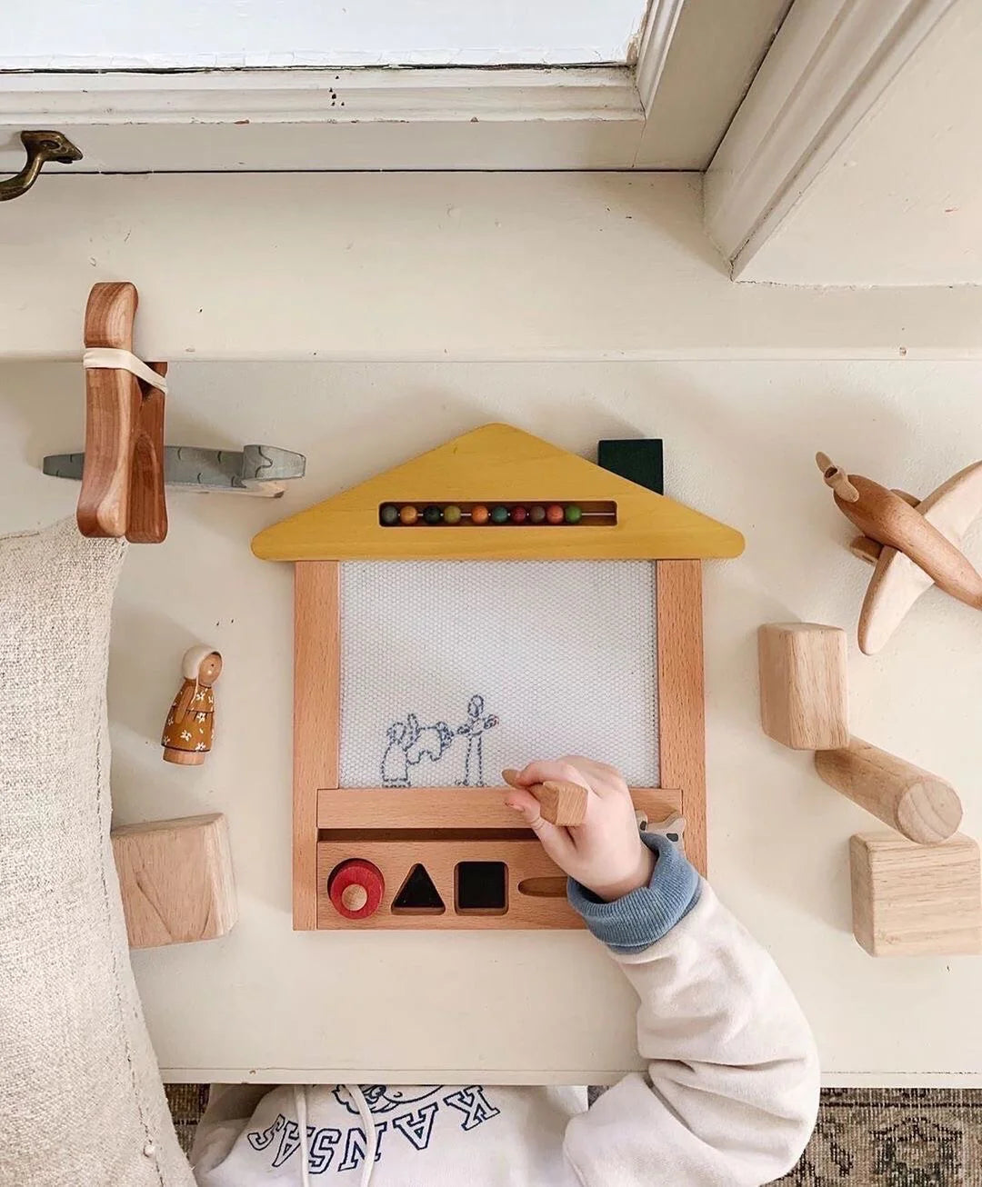 Main d'enfant avec Maison à dessin magique en bois