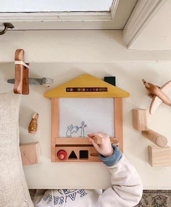 Main d'enfant avec Maison à dessin magique en bois