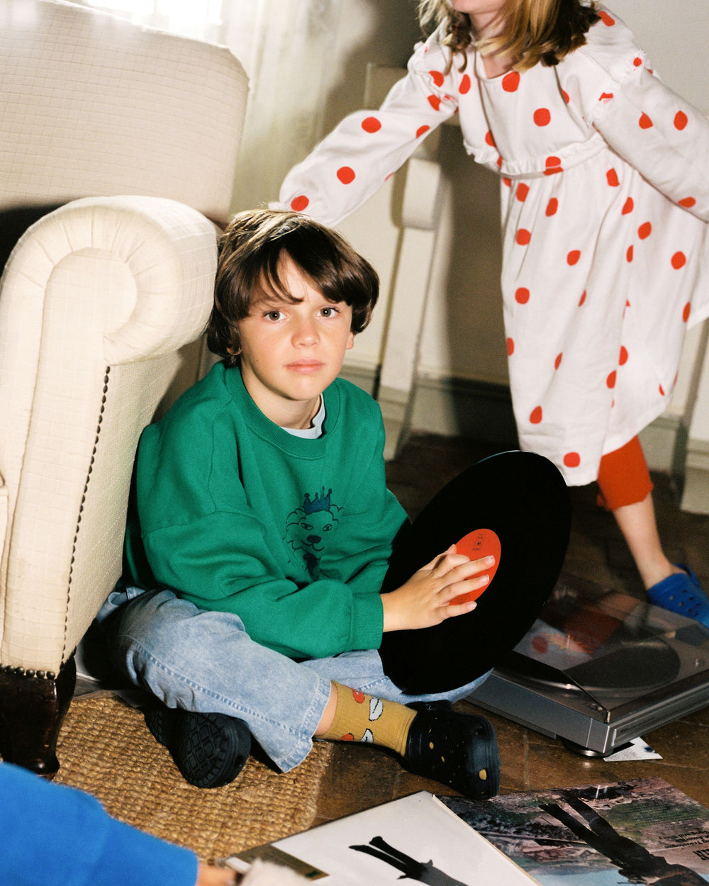 Enfant avec Pantalon délavé bleu clair et pull vert qui joue de la musique