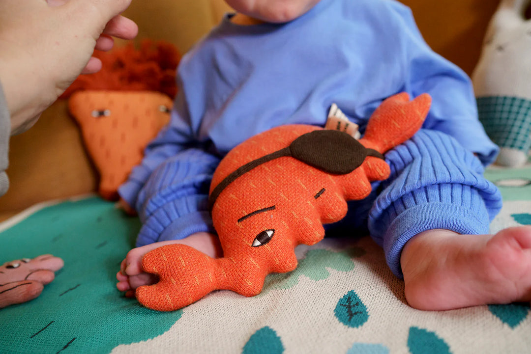 Bébé avec Peluche Donna Wilson en coton bio orange en forme de crabe