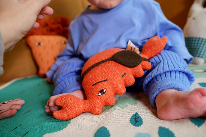 Bébé avec Peluche Donna Wilson en coton bio orange en forme de crabe
