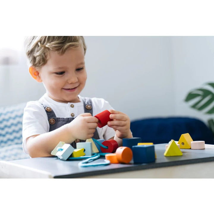 Enfant avec Perles géométriques en bois à enfiler
