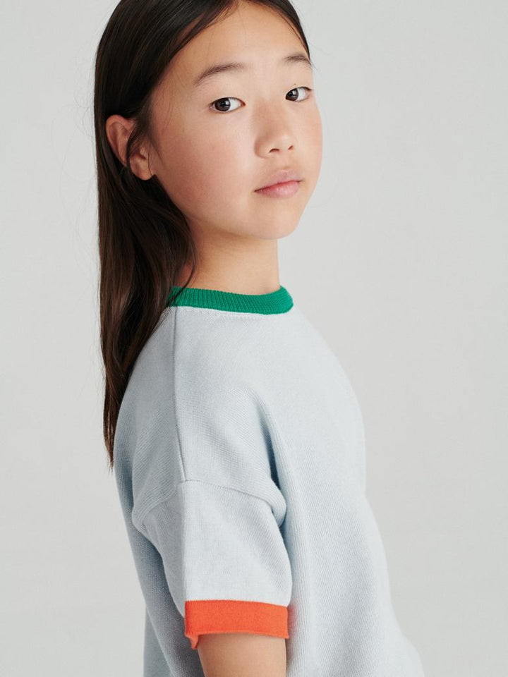 Fille avec T-shirt True Artist tricoté en coton bleu pâle avec détails oranges et verts