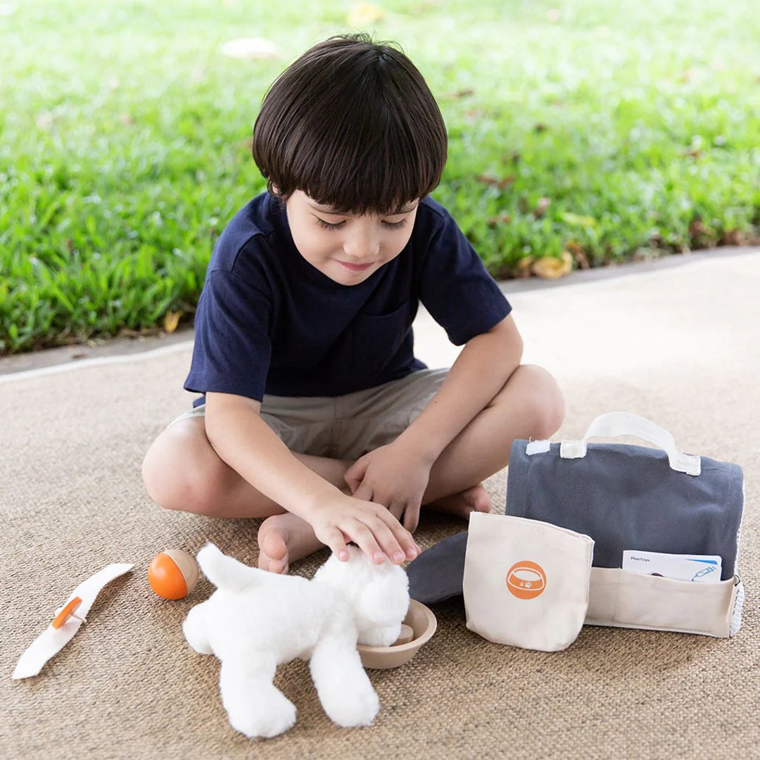 Enfant qui joue avec la Trousse de soins pour animaux de compagnie Plan Toys