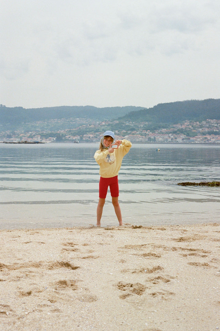 Fille à la plage avec Chandail en polaire 100% coton jaune avec imprimé cygne