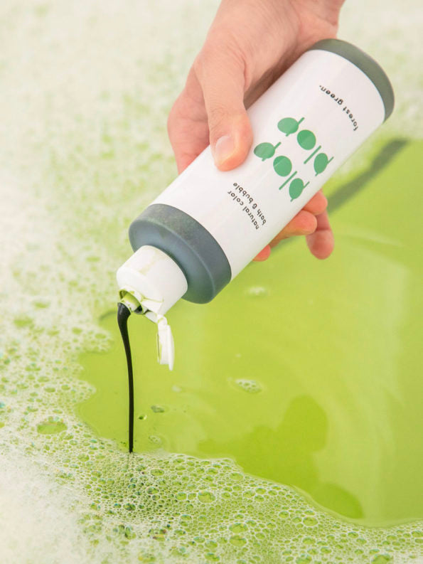 hand pouring plop plop nahthing project natural bubble bath bottle in forest green in bath water
