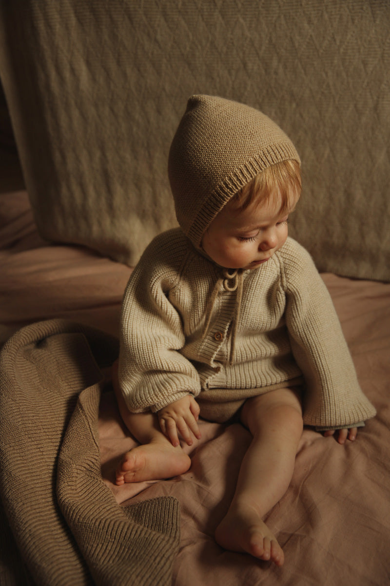 Bébé avec Bonnet tricoté sable