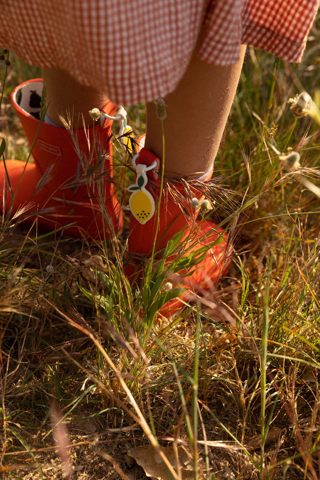 Jambes de fille avec Bottes de pluie en caoutchouc orange dans un jardin