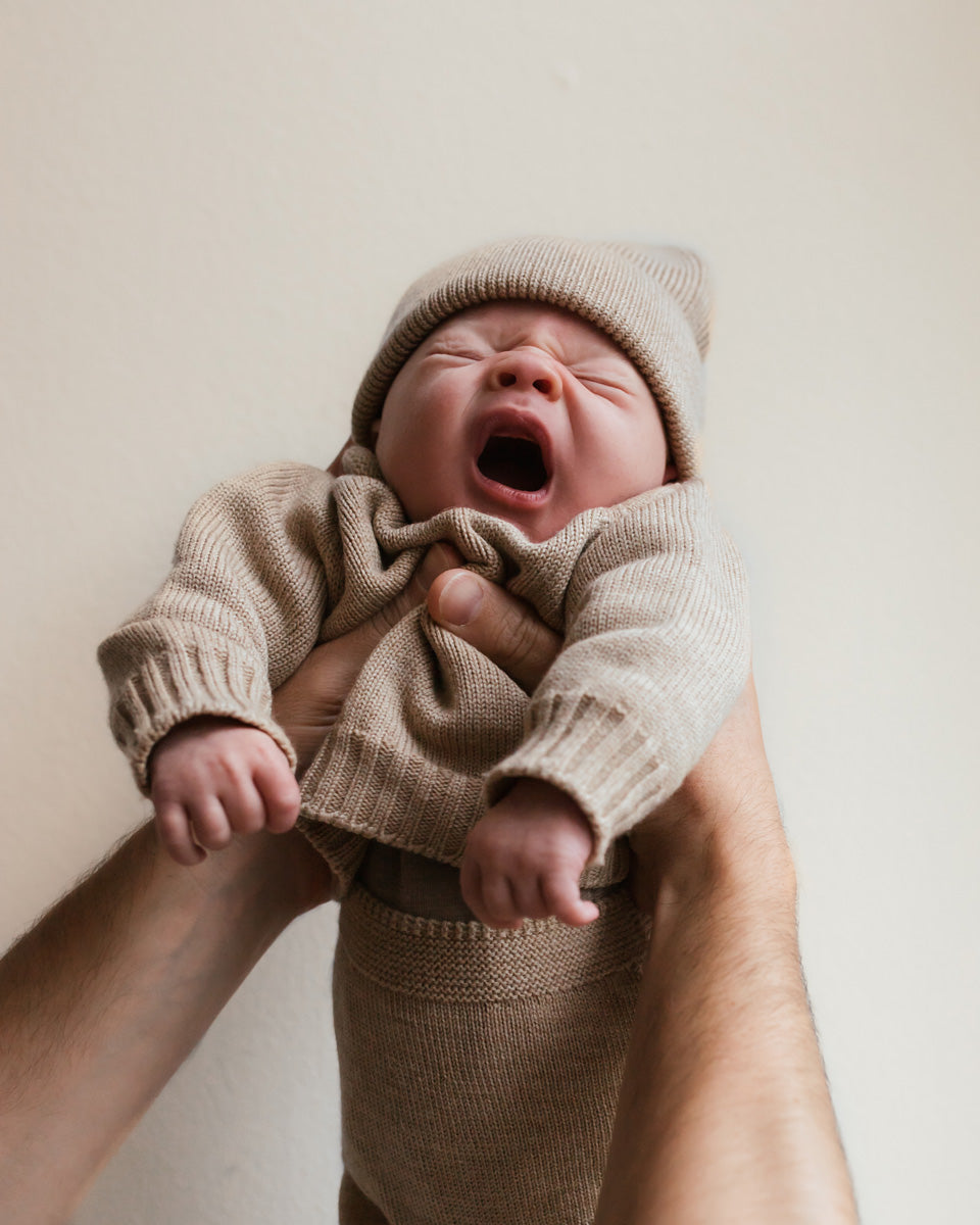 Bébé avec Cardigan tricoté en laine sable