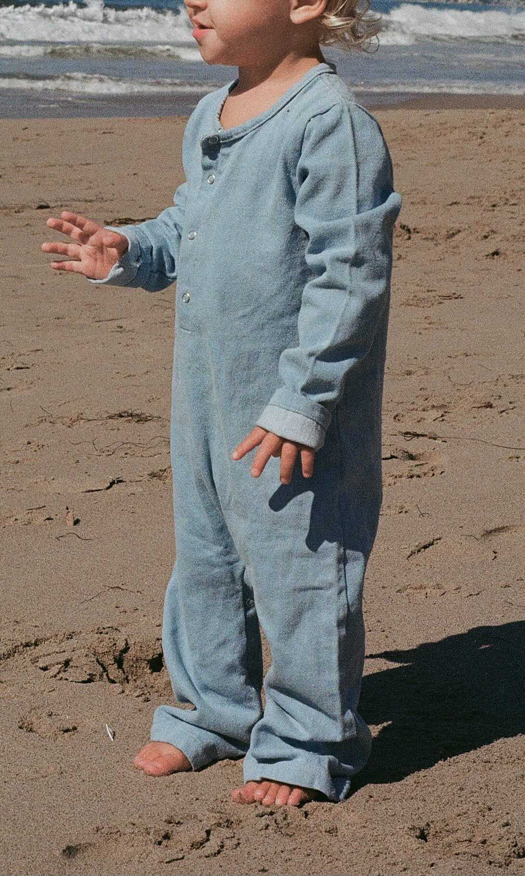 Bébé à la plage avec  Combinaison denim bleu clair