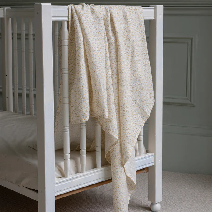 Couverture d'emmaillotage en coton avec imprimé marguerites sur un lit de bébé