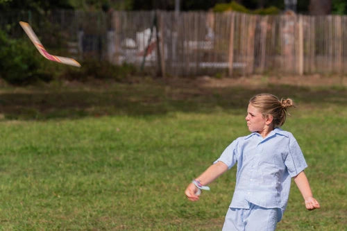 Enfant qui lance un boomerang en bois