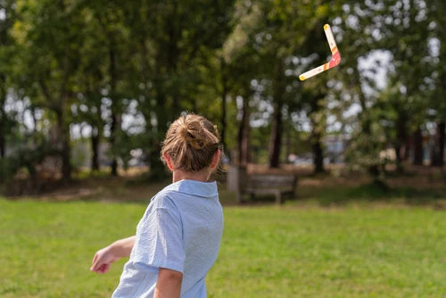 Enfant qui lance un boomerang en bois