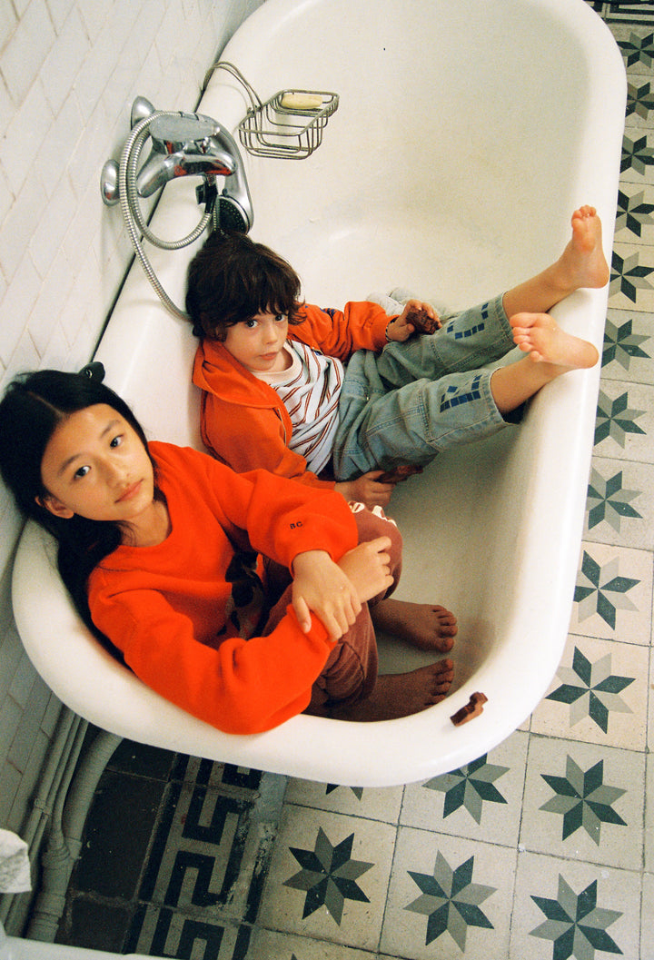 Enfants dans une baignoire vide avec des vêtements Bobo Choses 