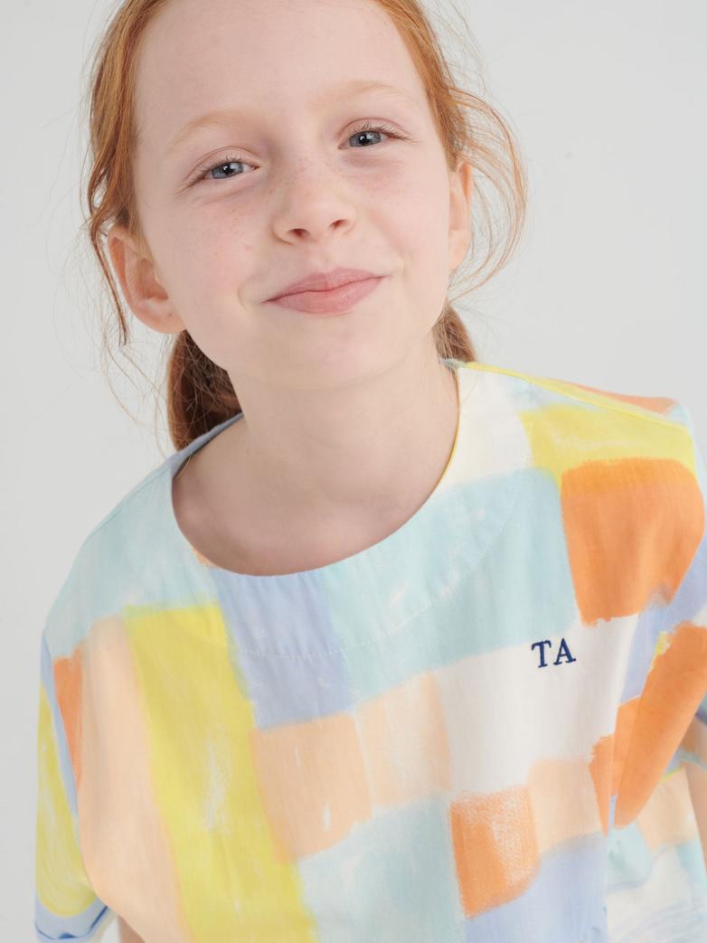 Fille avec Robe True Artist avec tissu coloré orange, jaune, bleu et blanc