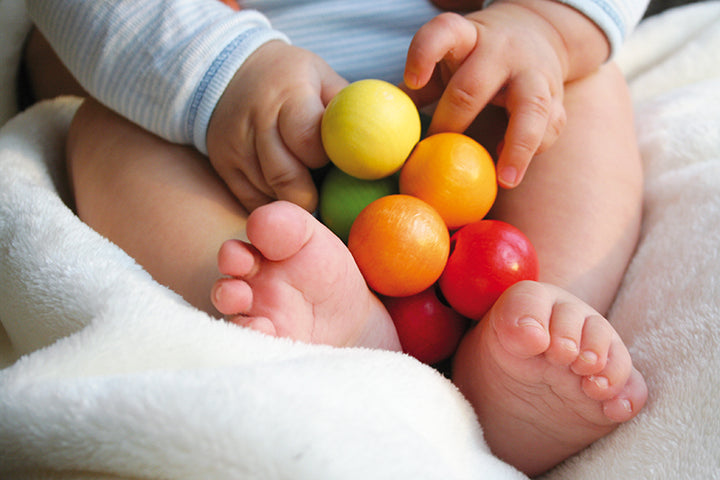 pieds et mains de bébé avec Hochet billes en bois multicolore à manipuler 