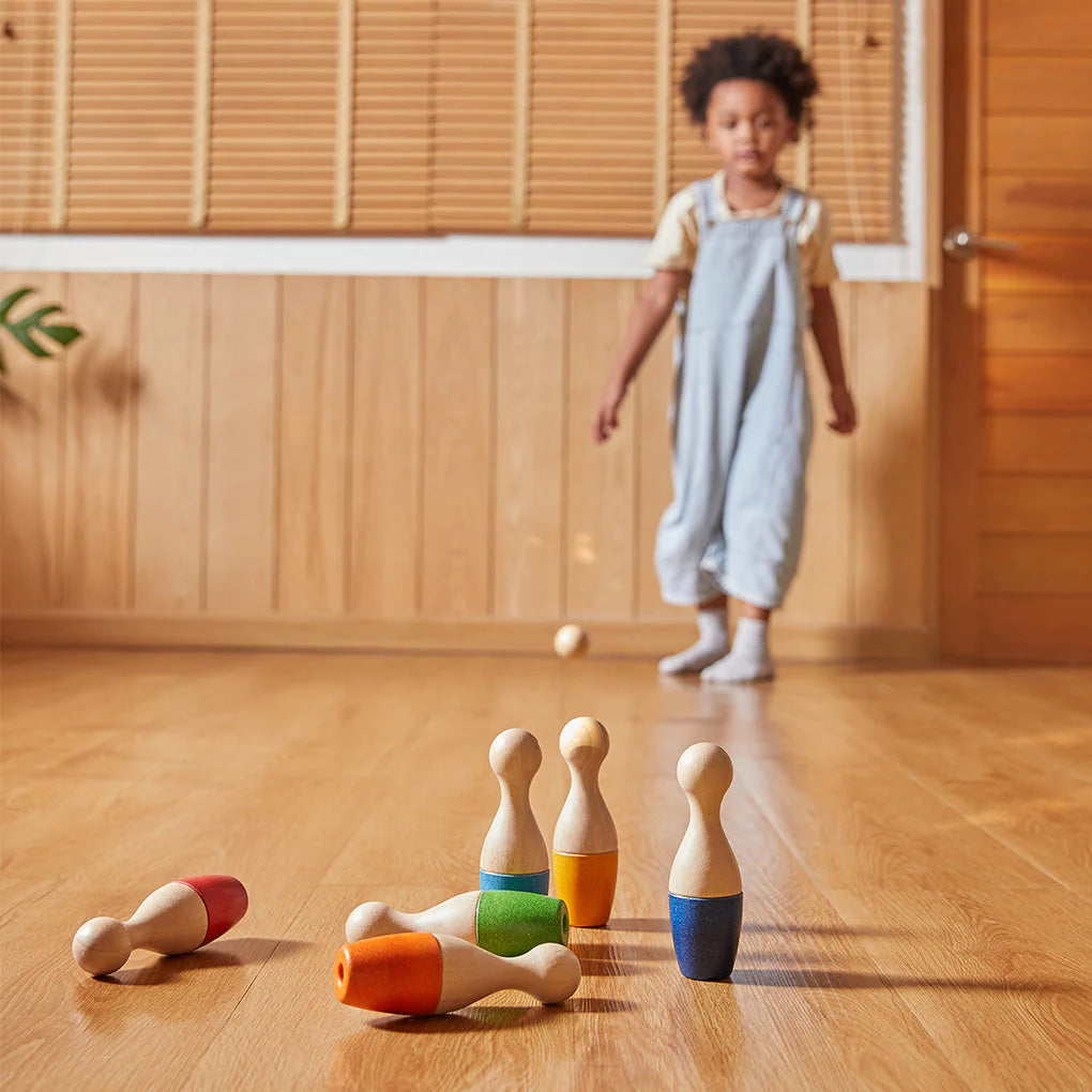 Enfant qui joue avec Jeu de quilles en bois Plan Toys