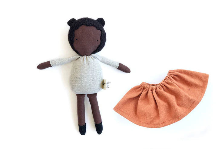 Mini poupée en laine et coton avec les cheveux noirs, la peau chocolat et une jupe brique