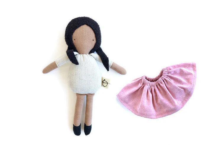 Mini poupée en laine et coton avec les cheveux longs noirs, la peau café au lait et une jupe rose