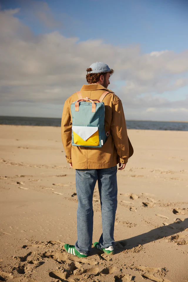 Homme à la plage avec Large Sac à dos Sticky Lemon bleu et jaune