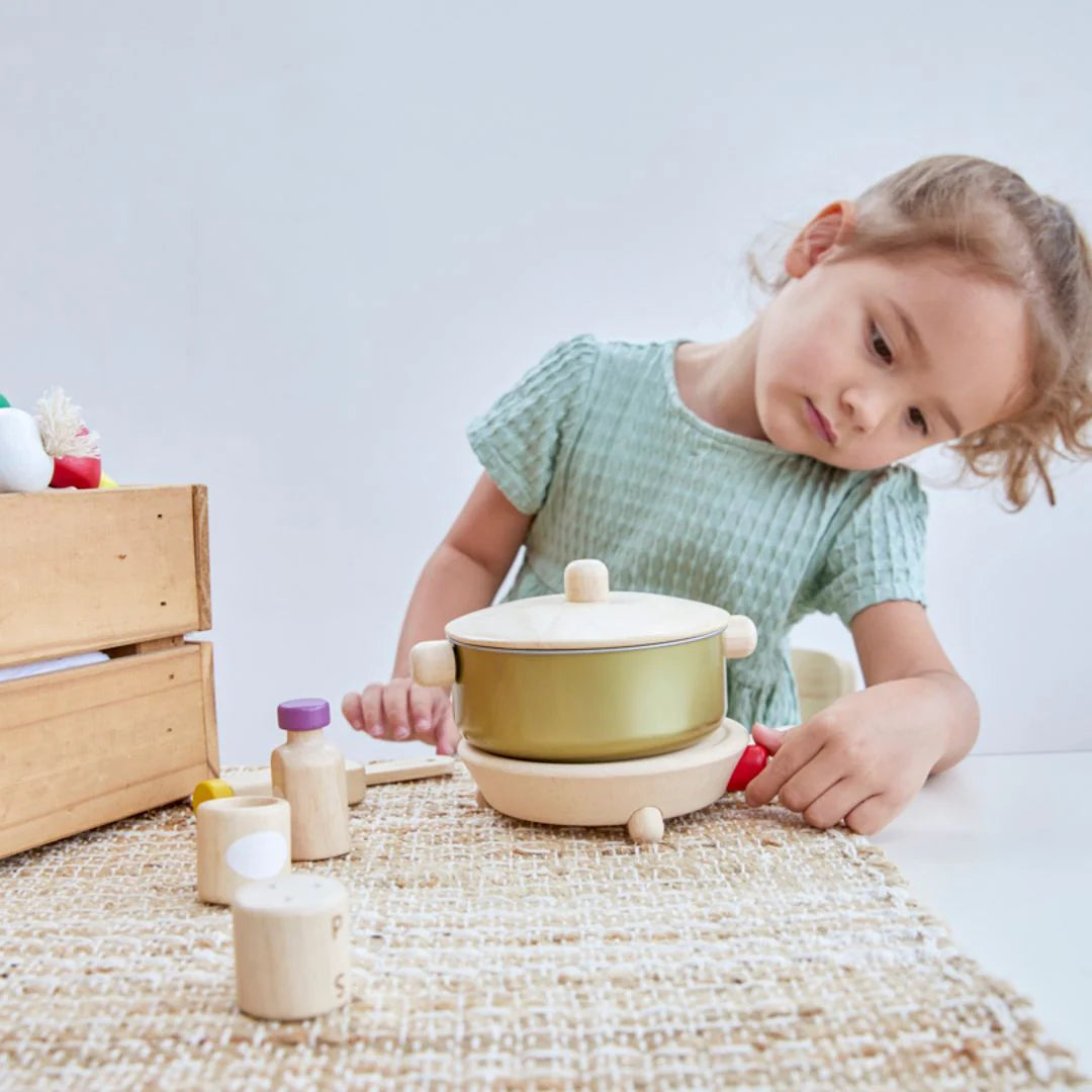 Fille qui joue avec Set de cuisine Plan Toys 