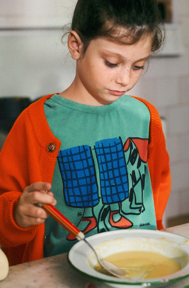 Enfant à table avec T-shirt Bobo Choses en coton vert avec imprimé chien et jambes d'enfant