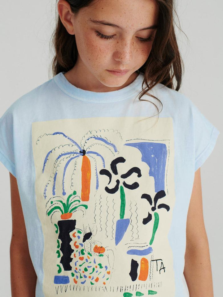 Fille avec T-shirt True Artist en coton bleu pâle avec imprimé fleurs et plantes
