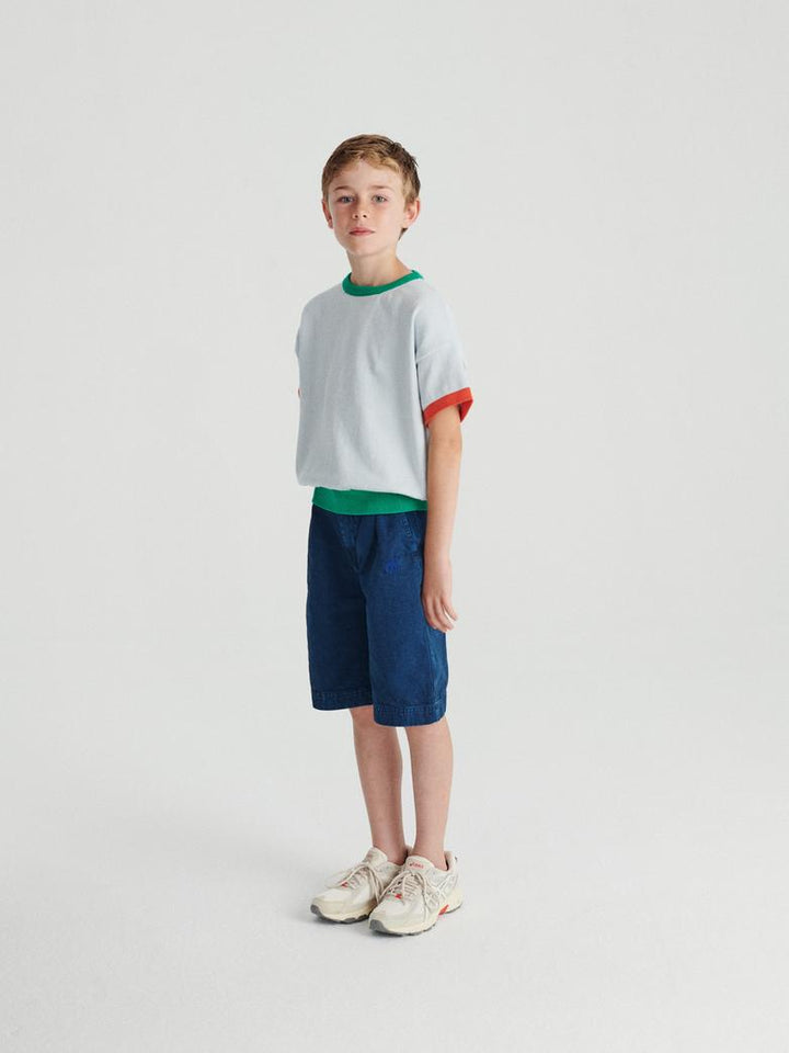 Garçon avec T-shirt True Artist tricoté en coton bleu pâle avec détails oranges et verts