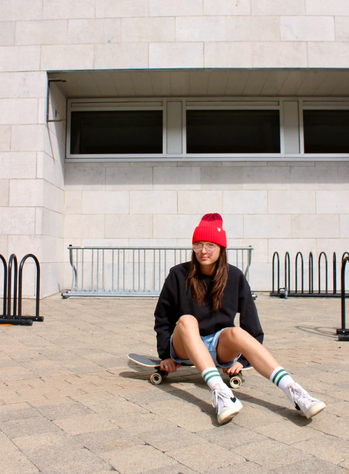 Fille sur une planche roulettes avec Tuque bicolore rouge et framboise