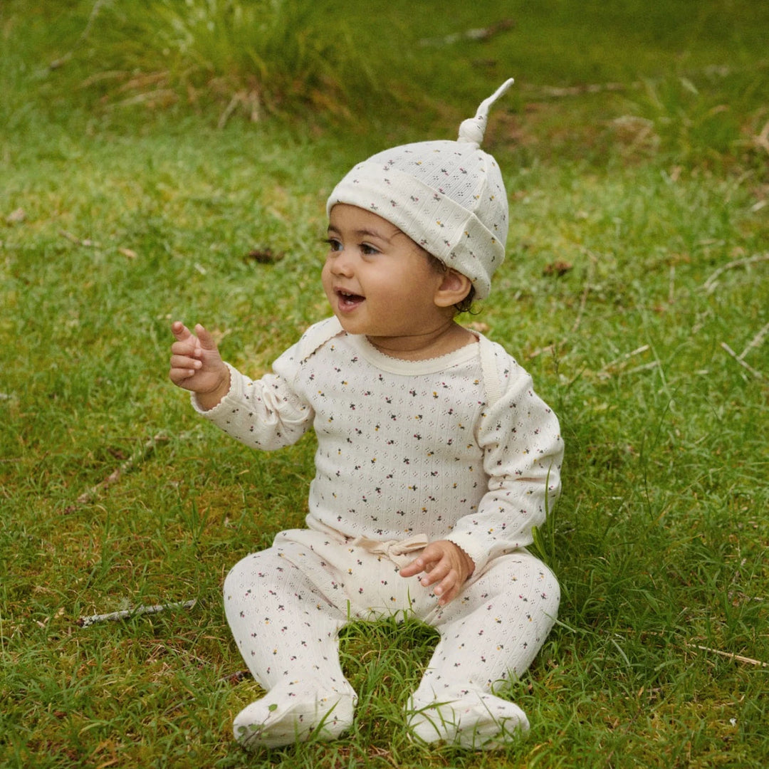 bébé dans un jardin avec Bonnet noué pointelle avec imprimé floral