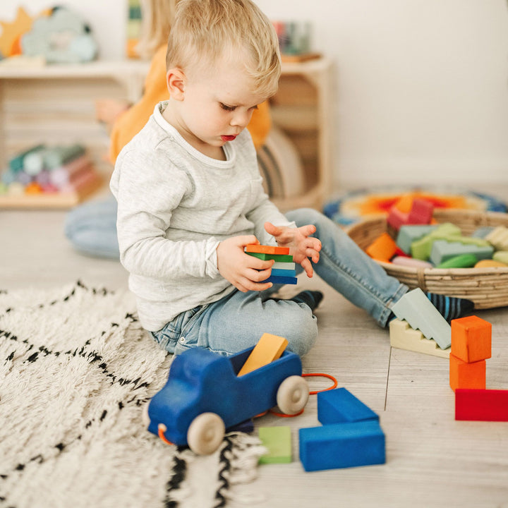 Enfant avec Camion en bois bleu à tirer avec planchettes arc en ciel