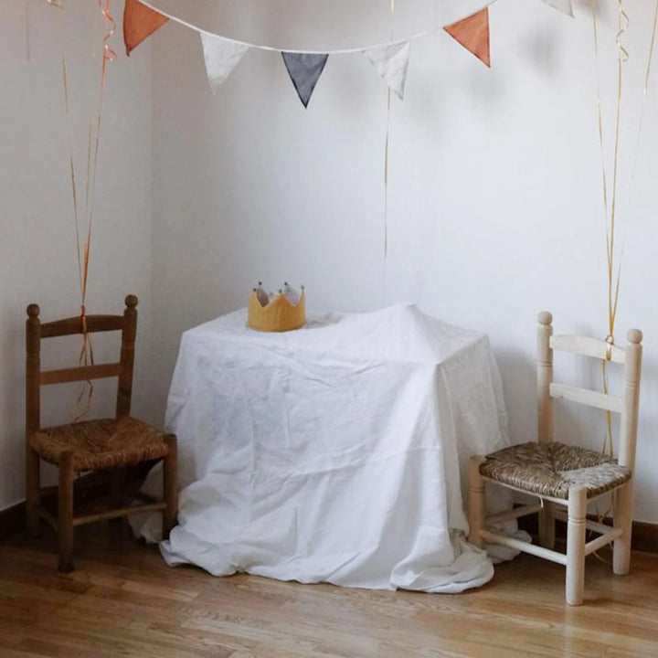 Couronne réversible en tissu jaune et écru avec pompons gris sur une table