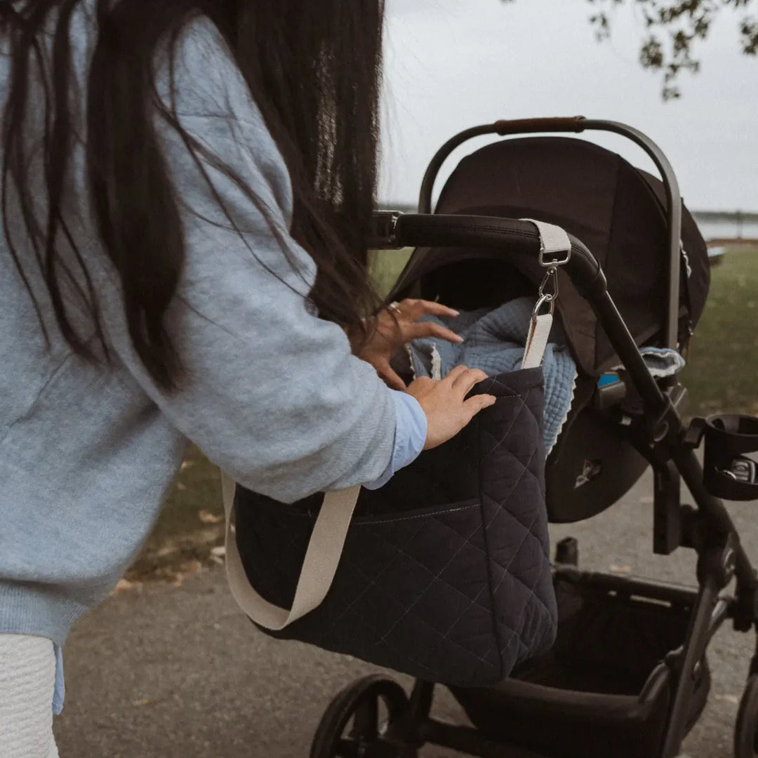 Femme avec Sac à couche matelassé en coton noir sur une poussette 