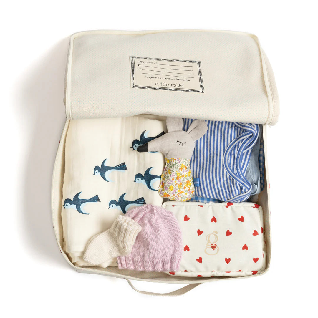 Valise en coton et lin blanc avec imprimé coeurs rouges avec des vêtements et accessoires pour bébé