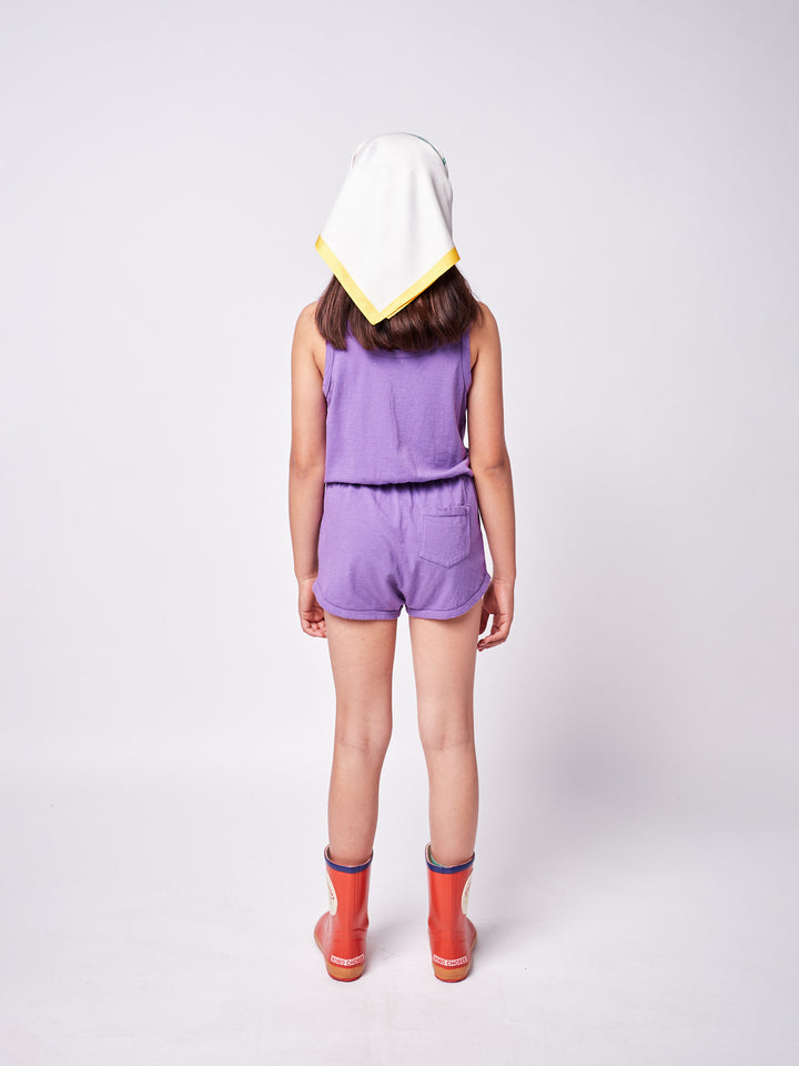 brown-haired little girl with purple bobo choses ''Beauty Everywhere'' playsuit, colorful headscarf and red rainboots, back