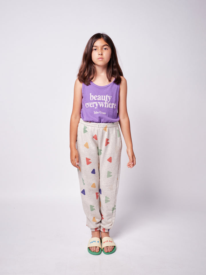 brown-haired little girl with purple bobo choses ''Beauty Everywhere'' playsuit and geometric multi-colored sweatpants