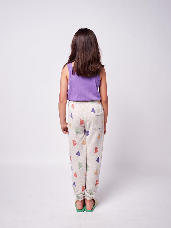 brown-haired little girl with purple bobo choses ''Beauty Everywhere'' playsuit and geometric multi-colored sweatpants back